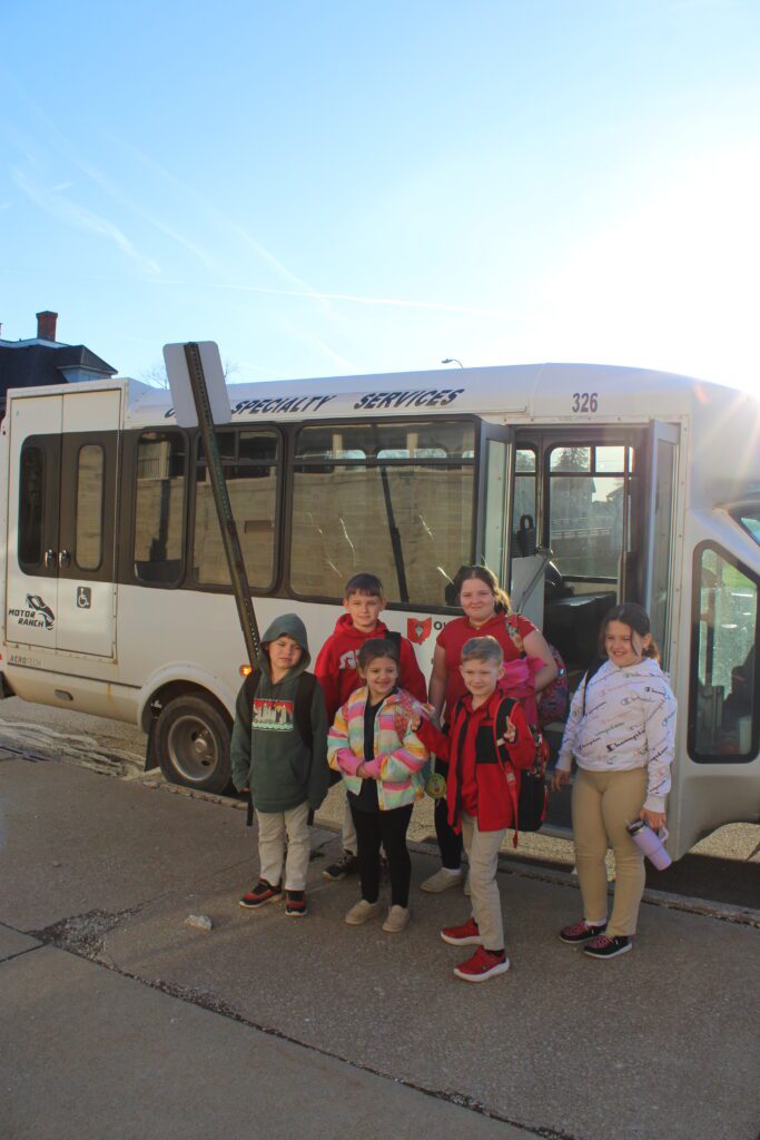 Group of St Joseph kids standing in front of their bus in the early morning of the school day