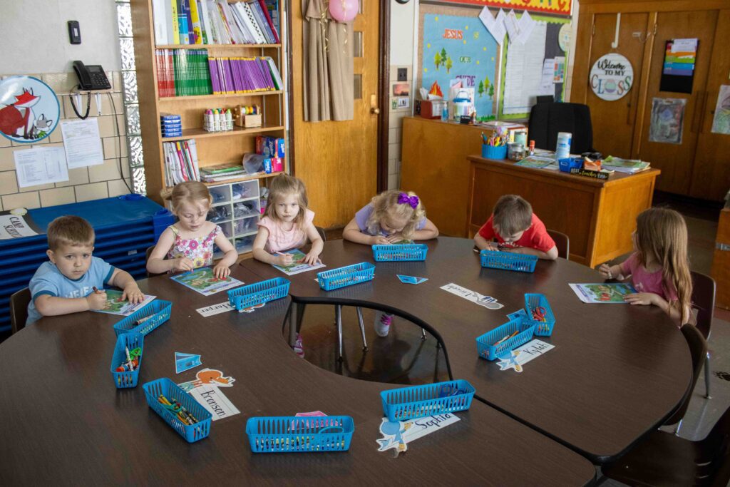 Preschoolers working on assignments at a round table together